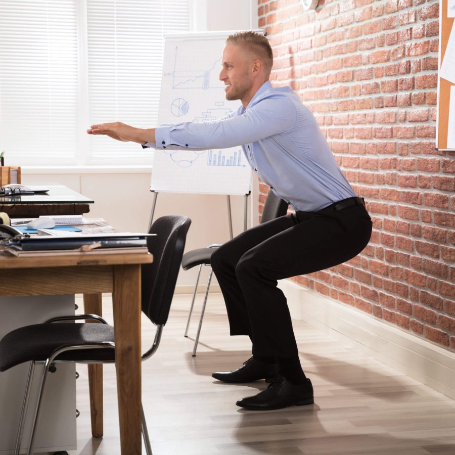 Happy Businessman Doing Exercise In Front Of Computer At Office